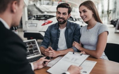 Happy beautiful couple is buying a new car at dealership.
